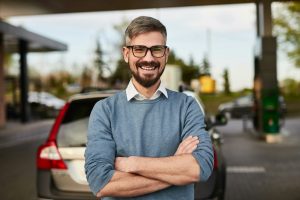 Happy male client smiling at camera standing near filling station